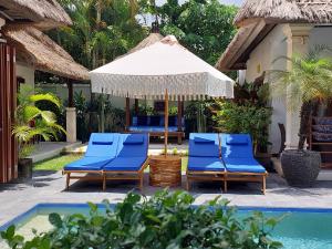 Beautiful Villa Indah في سمينياك: مجموعة من الكراسي الزرقاء ومظلة بجوار حمام السباحة