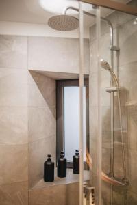 ein Badezimmer mit Dusche und drei Seifenflaschen auf einem Regal in der Unterkunft La Vie en Rose - Luxe, calme & hypercentre - 3* in Annecy