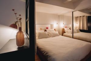 um quarto com duas camas e um vaso sobre uma mesa em La Vie en Rose - Luxe, calme & hypercentre - 3* em Annecy