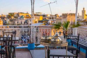 a balcony with tables and chairs and a view of a city at Dar lmrama Guest House Fes Medina Morocco in Fès