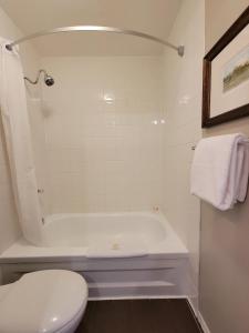 La salle de bains est pourvue d'une baignoire blanche et de toilettes. dans l'établissement The Georgetown Inn, à Canmore