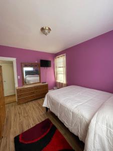 a bedroom with purple walls and a bed and a mirror at Home Away From Home in Wakefield