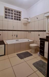 uma casa de banho branca com uma banheira e um WC em Casa com banheira para até 12 pessoas prox USP-HC fácil acesso para Arena EUROBIKE com Wi-Fi em Ribeirão Preto