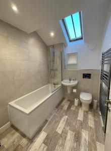 a bathroom with a tub and a toilet and a sink at Ebor Mill's Cottage in Haworth