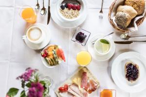 einen Tisch mit Frühstücksteller und Getränken in der Unterkunft Hotel Baumwirt in Kastelruth