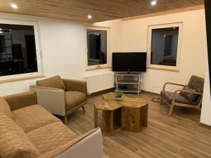 a living room with a couch and a tv at Le chalet du kanal in Winseler