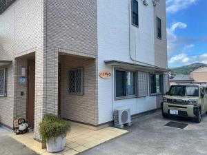 une voiture garée devant un immeuble dans l'établissement ビーチ徒歩１分のプライベート空間、民宿やまぐち, à Susami