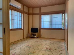 ビーチ徒歩１分のプライベート空間、民宿やまぐち في Susami: غرفة معيشة فارغة مع تلفزيون ونوافذ