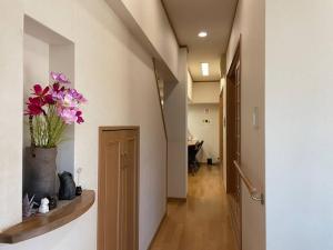 ビーチ徒歩１分のプライベート空間、民宿やまぐち في Susami: ممر به إناء من الزهور على الحائط