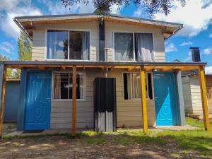 a white house with blue doors and windows at Departamentos el Maiten in El Bolsón