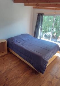 a bed in a room with a large window at Barrio Arrayanes in El Bolsón +2 photos