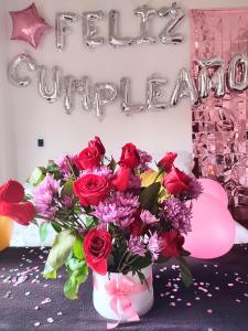 un jarrón lleno de rosas rojas y un signo de feliz cumpleaños en Hotel Villasaurio, en Sáchica