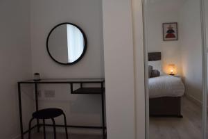 Dormitorio con espejo, cama y taburete en Modern 2 Bed house - HS2, NEC & Birmingham Airport, en Marston Green