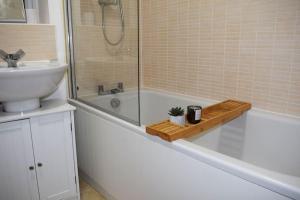 ein Badezimmer mit einem Waschbecken und einer Badewanne mit einem Waschbecken in der Unterkunft Modern 2 Bed house - HS2, NEC & Birmingham Airport in Marston Green