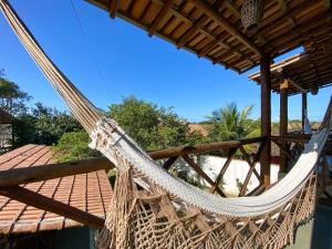 a hammock on a house with a view of the beach at Pousada Tamikuã in Caraíva