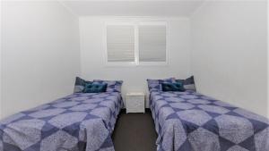 扬巴Craigmore on the Beach unit 6的带窗户的房间里有两张单人床