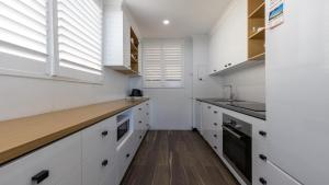 扬巴Craigmore on the Beach unit 6的配有白色橱柜和木质台面的厨房 更多1张照片