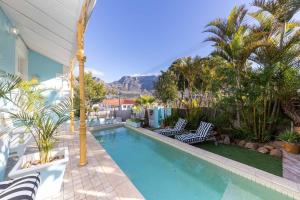 una piscina con sillas, árboles y una montaña en Amina Boutique Hotel, en Ciudad del Cabo