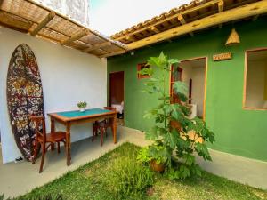 a patio with a table and chairs and a green wall at Pousada Tamikuã in Caraíva