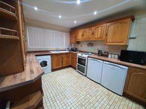 a kitchen with white appliances and wooden cabinets at 5 Bedroom House by monishortlets in Dagenham