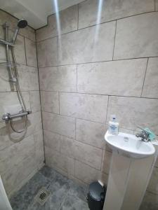 ein Badezimmer mit einem weißen Waschbecken und einer Dusche in der Unterkunft 5 Bedroom House by monishortlets in Dagenham