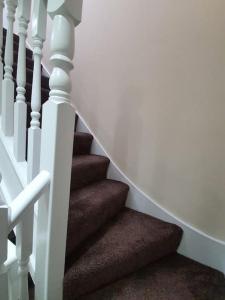 eine Treppe mit einer weißen Schiene und einer braunen Treppe in der Unterkunft 5 Bedroom House by monishortlets in Dagenham