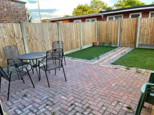 a patio with a table and chairs and a fence at 5 Bedroom House by monishortlets in Dagenham