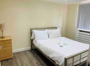 um quarto com uma cama com lençóis brancos e uma janela em 5 Bedroom House by monishortlets em Dagenham