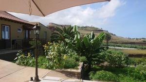 an umbrella in front of a house with a garden at Tantulia Las Tapias Tenerife in Puerto de la Cruz