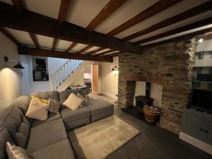 a living room with a couch and a stone fireplace at Abbey Cottage in Llangollen