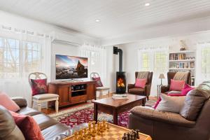a living room with couches and a table and a tv at Lou Lous Cottage Bowral Southern Highlands in Bowral