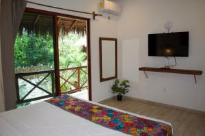 a bedroom with a bed and a tv and a window at Aldea San Lam - Oasis Of Tulum in Tulum