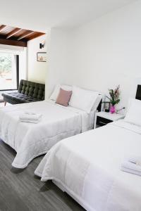 two white beds in a room with a couch at Hotel Casa Luna in Cúcuta