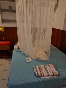 a bed with a curtain and a towel on it at Chez Gisèle et Philippe in Terre-de-Haut