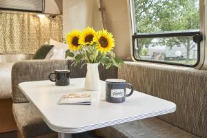 a table with two cups and a vase with sunflowers on it at The Vintages Trailer Resort in Dayton