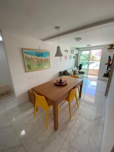 un soggiorno con tavolo in legno e sedie gialle di Makambira Residence 201 a Porto De Galinhas