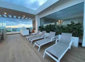 balcón con sillas blancas y vistas a la ciudad en 1BR Luxury apartment Pool, gym, rooftop Santo Domingo, en Santo Domingo