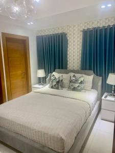 1 dormitorio con 1 cama grande y cortinas azules en 1BR Luxury apartment Pool, gym, rooftop Santo Domingo en Santo Domingo