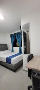 a bedroom with a bed with blue curtains and a desk at Andaliving Campo Valdes Hospedaje in Medellín