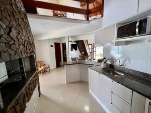 a kitchen with white cabinets and a stone wall at Casa a 50 M do Mar Para Recarregar as Energias in Bombinhas