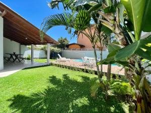 a backyard with a swimming pool and a yard with grass at Casa a 50 M do Mar Para Recarregar as Energias in Bombinhas