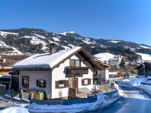 une maison blanche avec de la neige sur le toit dans l'établissement Ferienhaus Rieder, à Hopfgarten im Brixental