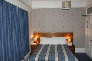 a bedroom with a large bed with a blue curtain at Kirkdale Hotel in Croydon