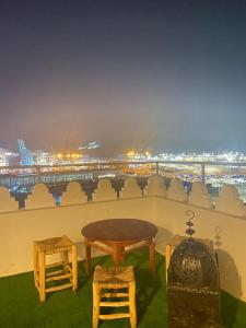 d'une table et de chaises sur un balcon avec vue sur la ville. dans l'établissement Appartement a ksar SGHIR en face du terminal passagers de Ferry port Tanger Med, à Ksar Sghir