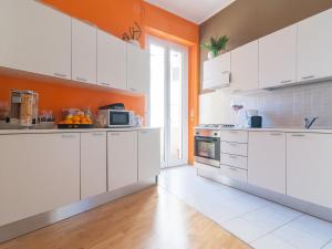 una cucina con armadi bianchi e parete arancione di Affittacamere Art Rooms a Cagliari