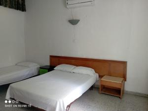 a small bedroom with two beds and a table at Hotel Albatros in El Espinal