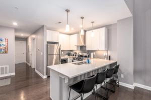 a kitchen with white cabinets and a large island with bar stools at Soaring 2-Bedroom Parkside Loft Walkable to it All in Cincinnati