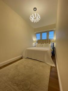 a bedroom with a large bed and a chandelier at Brand New Modern Flat in Southall