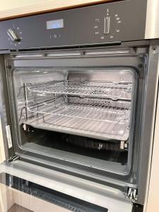 an open oven with a rack inside of it at Brand New Modern Flat in Southall