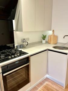 a kitchen with white cabinets and a stove top oven at Brand New Modern Flat in Southall